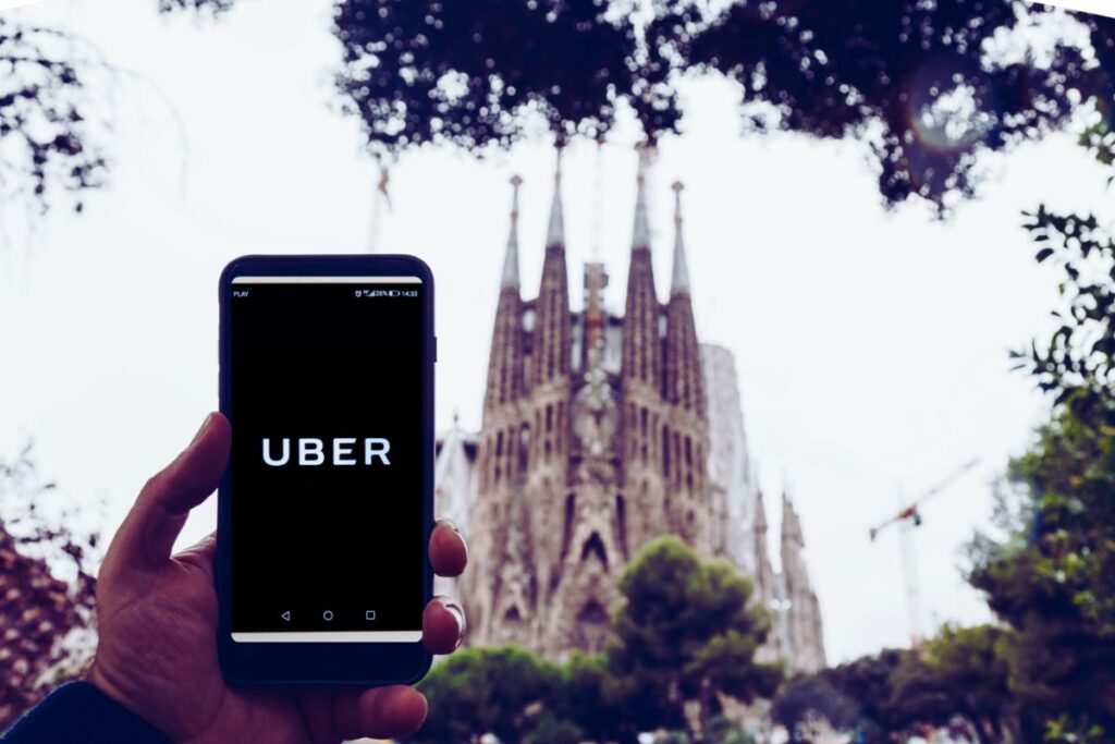 Hand holding a phone with the UBER app on it in front of the Sagrada Familia in Barcelona - Uber in Barcelona Spain